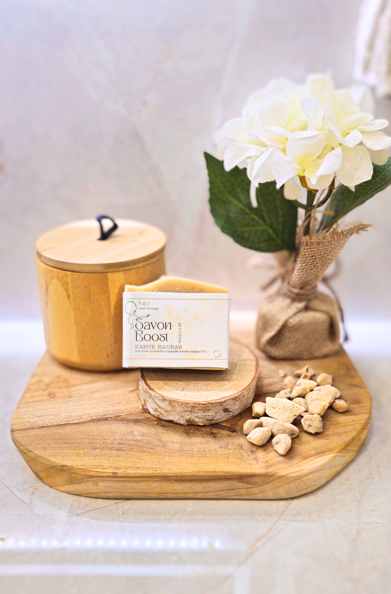Savon BOOST Karité Baobab présenté sur un plateau en bois avec des éclats de pulpe de baobab. Soin nourrissant et réparateur pour une peau douce et hydratée.